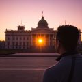O siluetă în fața Parlamentului României, la apus.